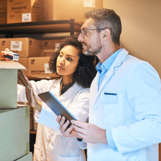 Une femme et un homme contrôlent les médicaments livrés dans un carton.