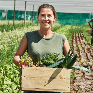 Agricultrice et cagette avec sa cueillette de légumes produits localement